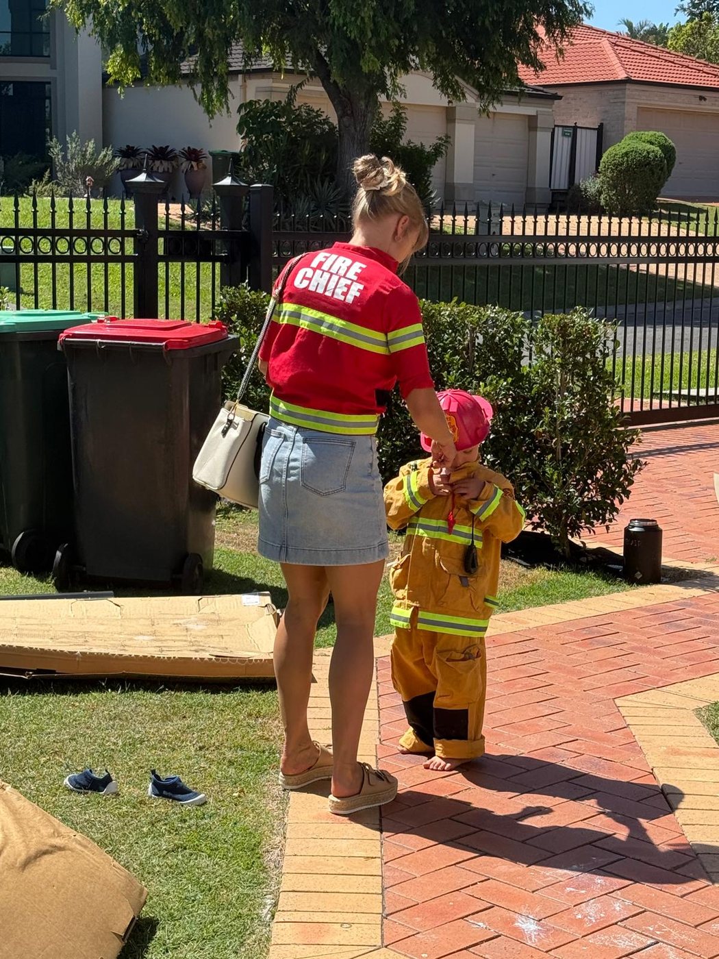 Sally in a fire chief shirt holding hands with her son in his little firefighter suit